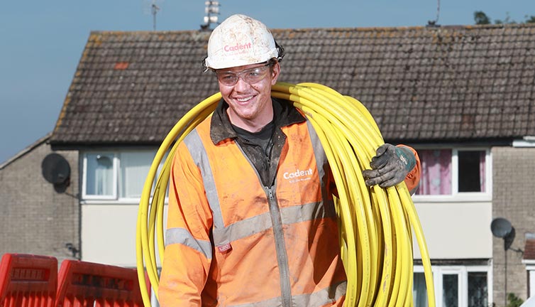 Cadent engineer carrying pipe with smile