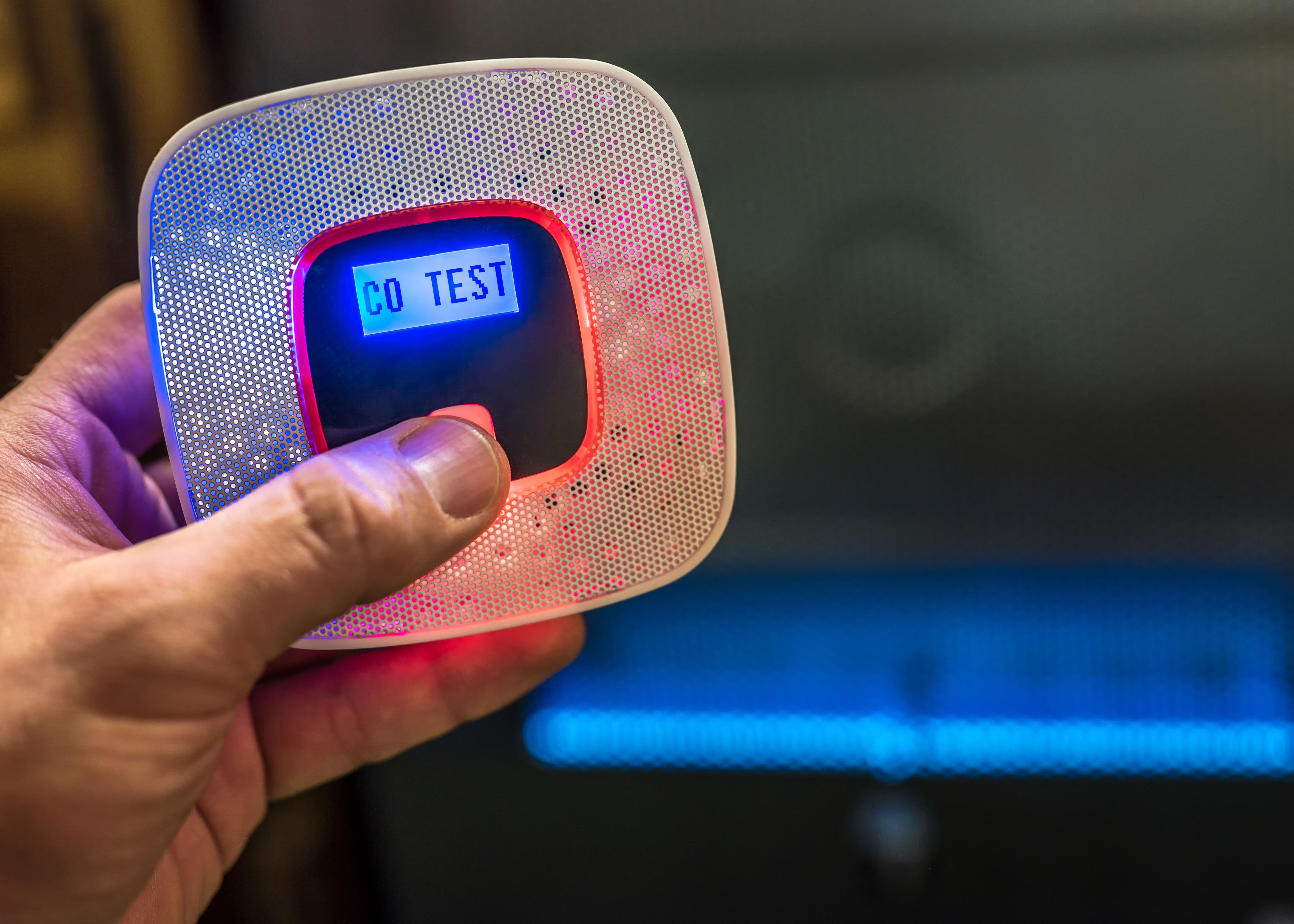 A person testing a carbon monoxide alarm