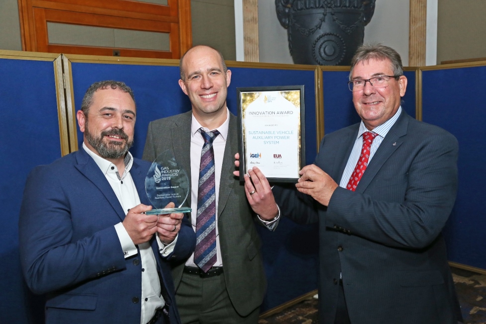 Three individuals holding an Innovation Award plaque and a glass trophy at an industry event
