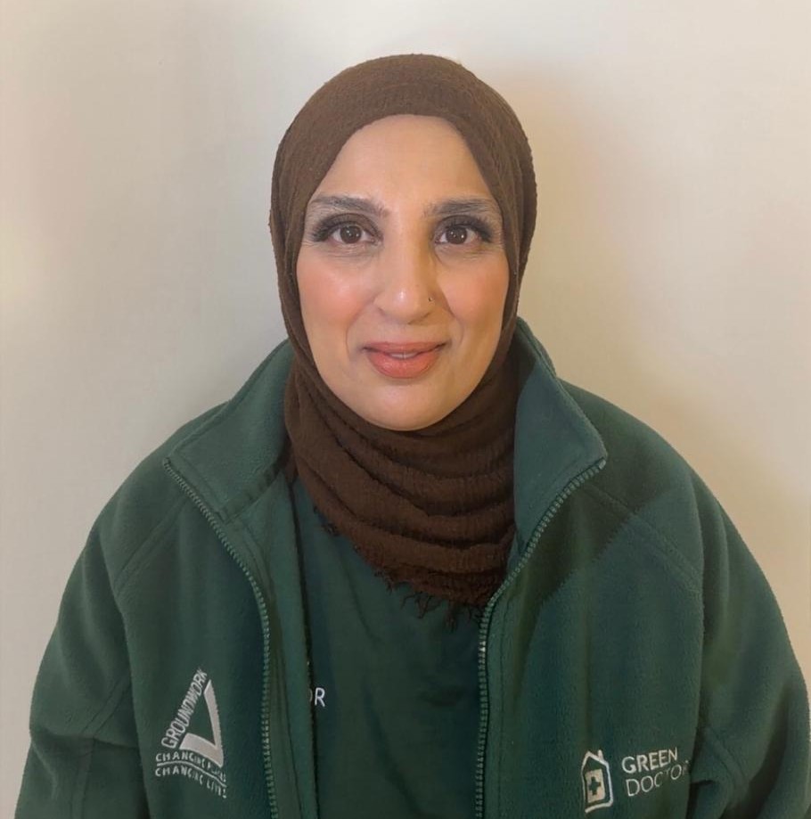 A woman smiles warmly at the camera, wearing a green jacket with "Green Doctor" and "Groundwork" logos, set against a plain background.