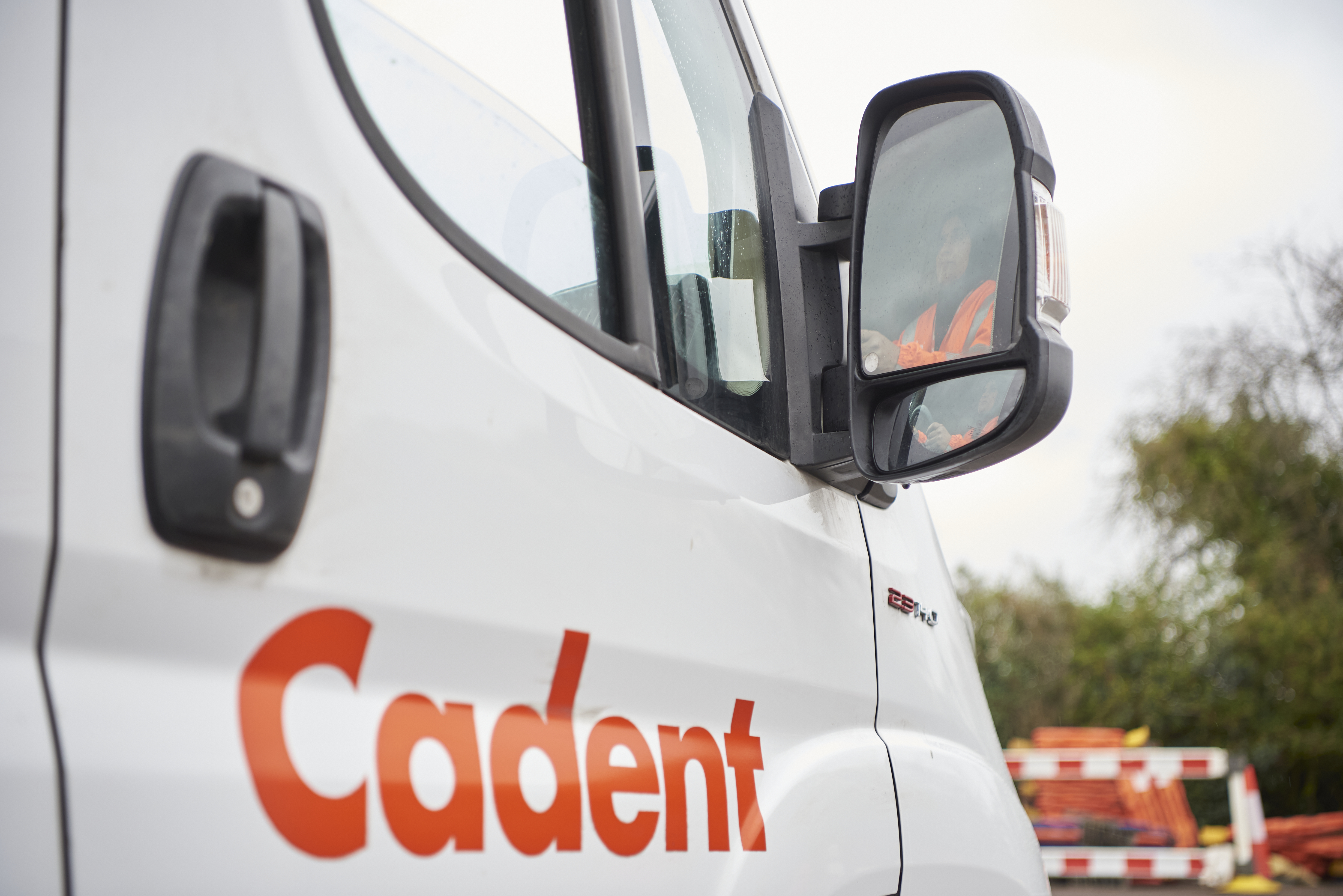 Close up image of a Cadent Van, zooming in on the brand’s logo. An engineer can be seen in the van through the reflection of the side-view mirror.