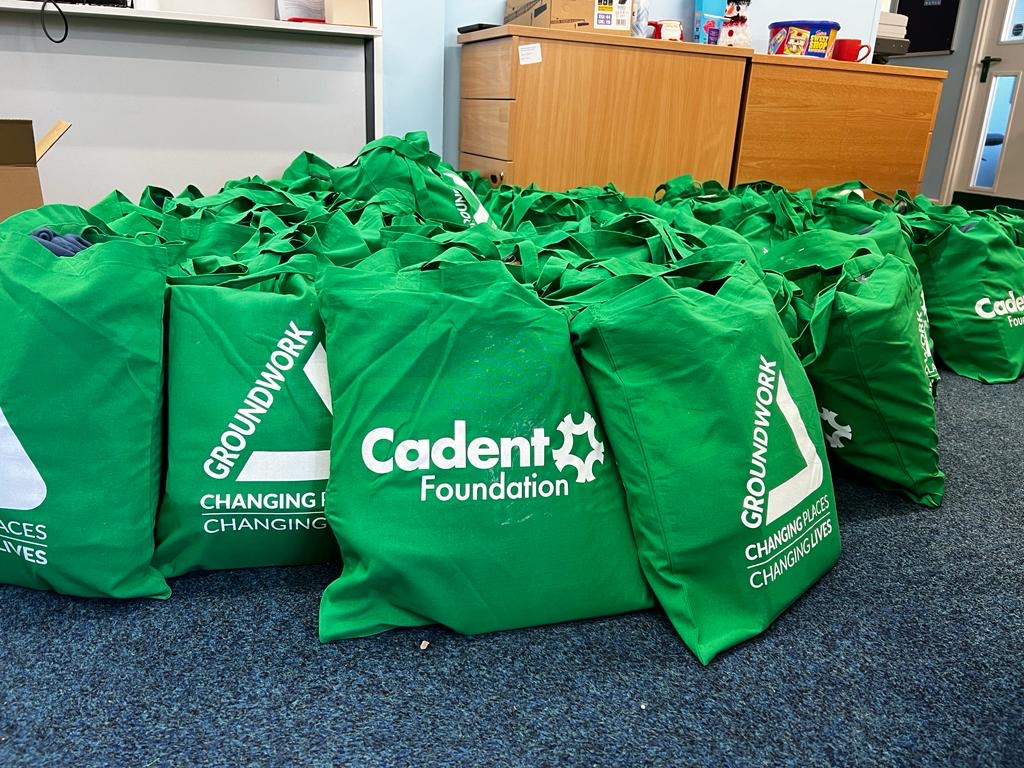 Green tote bags with white logos and text reading 