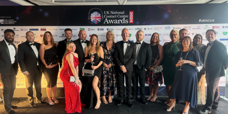 A Group of people on stage posing for a photoshoot on an award ceremony with a trophy on hand being displayed.