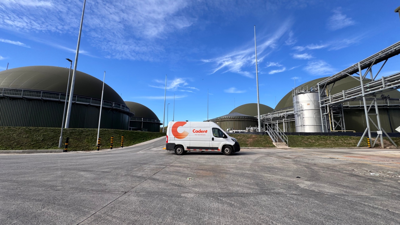 A white Codent service van sits in an industrial plant yard, surrounded by large domed tanks and metal pipes beneath a bright blue sky.
