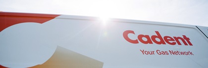 A white van with 'Cadent Your Gas Network' logo in red, set against a bright sunlit sky. The van features an orange and white graphic design.