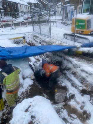 Person in orange and yellow vest working in snow